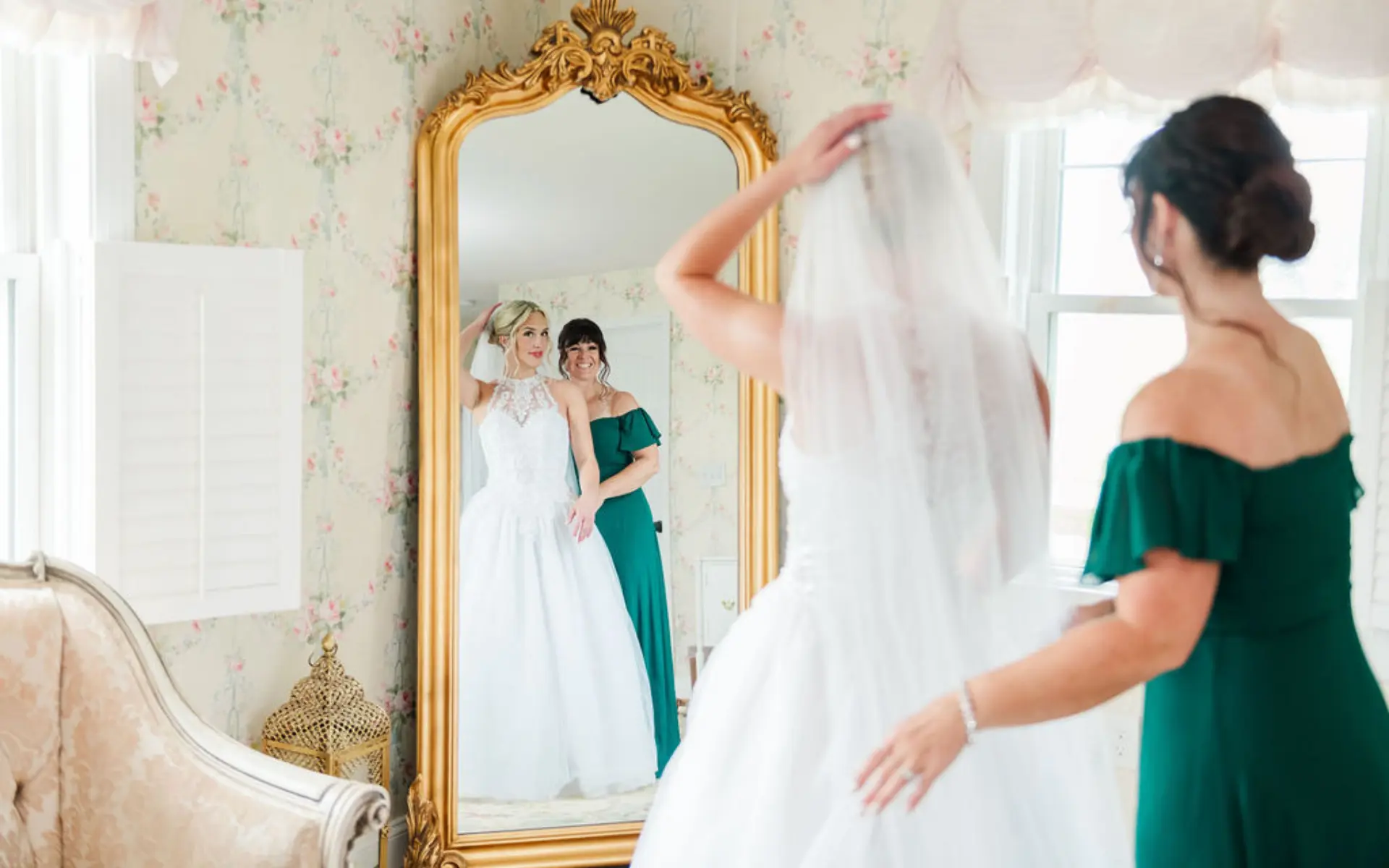 Bride and her mom looking together into the mirror while she gets ready